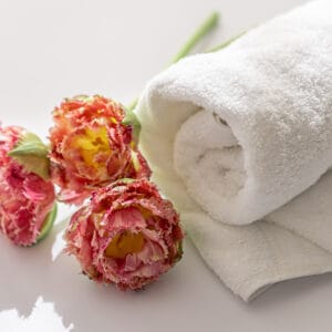 Close up, white terry bath towels and flowers.