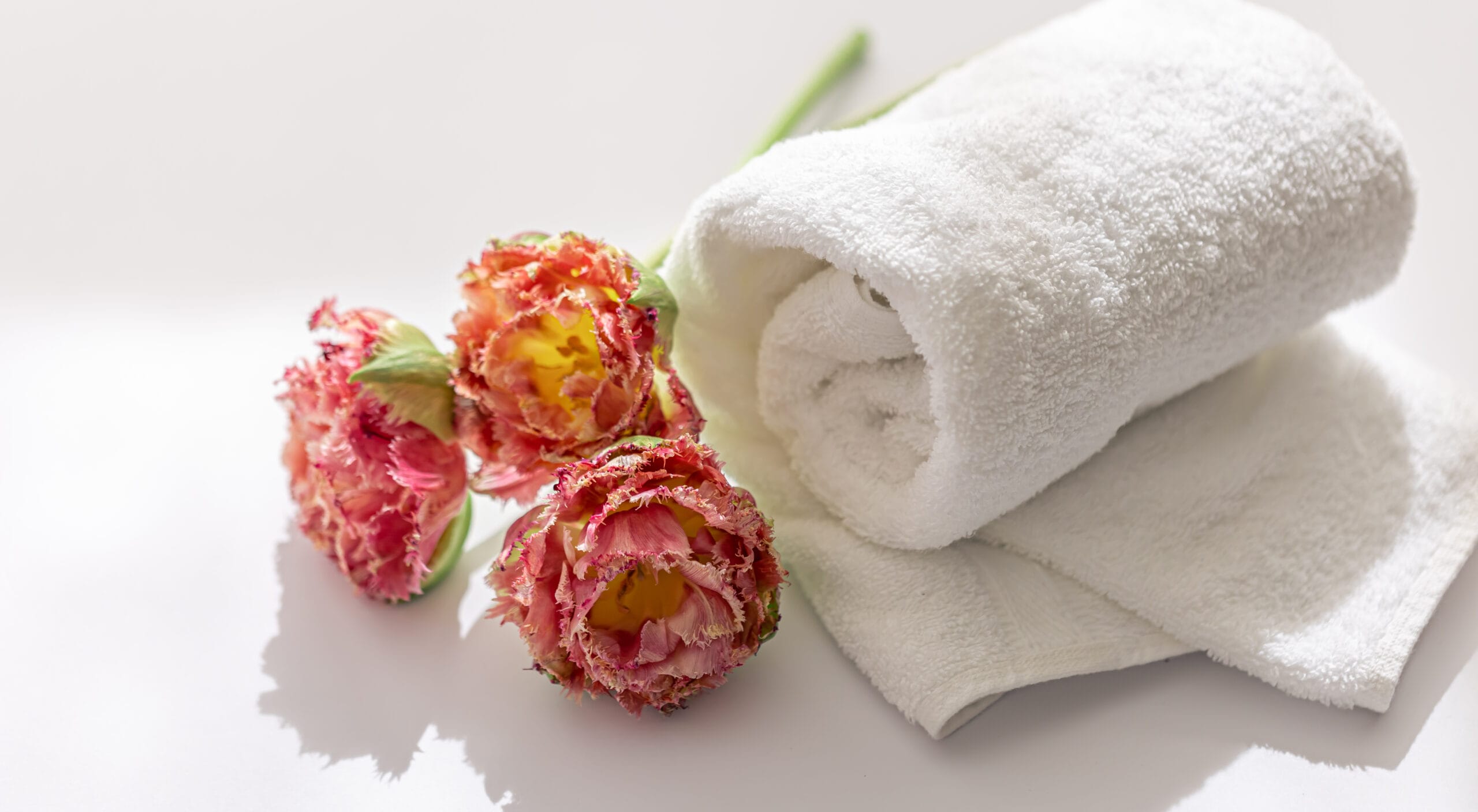Close up, white terry bath towels and flowers.